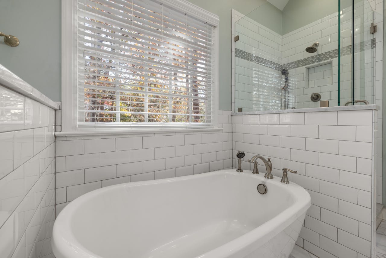 A spacious bathroom featuring a luxurious freestanding tub and glass shower surrounded by subway tiles.