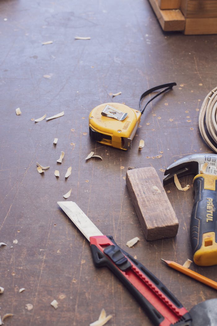Close-up of various woodworking tools scattered on a wooden workshop surface.